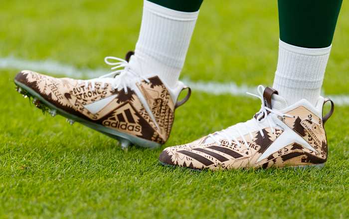 View of Aaron Rodgers' brown and white Adidas cleats.
